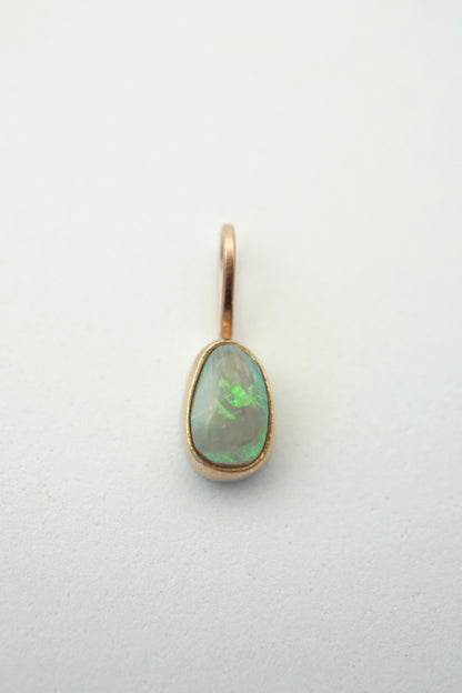 Gold pendant with a green gemstone on a light gray background