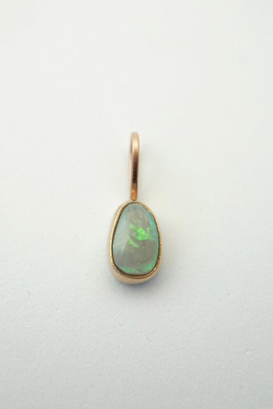 Gold pendant with a green gemstone on a light gray background