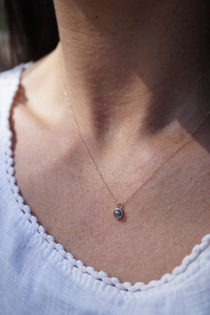 Gold Necklace with a small diamond pendant worn by a person against a neutral background